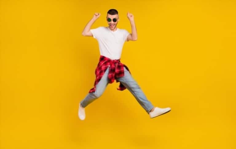 a man wearing checkered shirt with light jeans, white sneakers on the yellow background