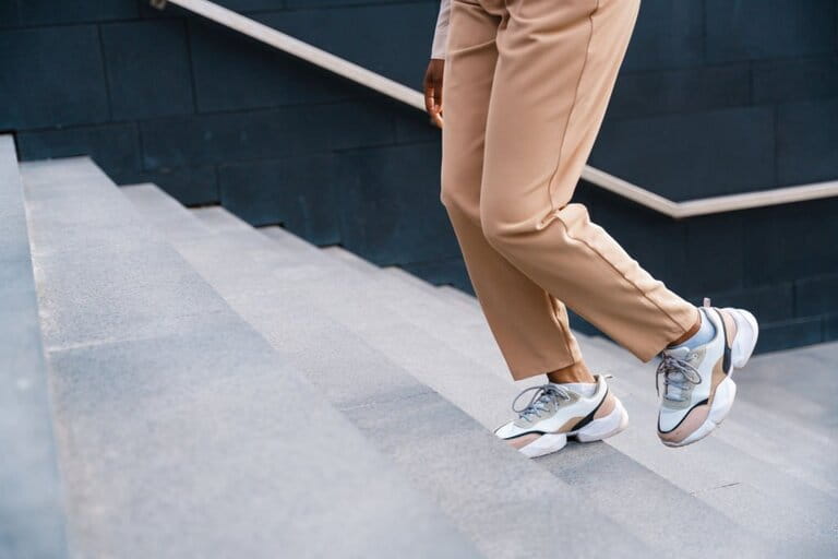 A pair of female feet with attractive sneakers, climbing the stairs